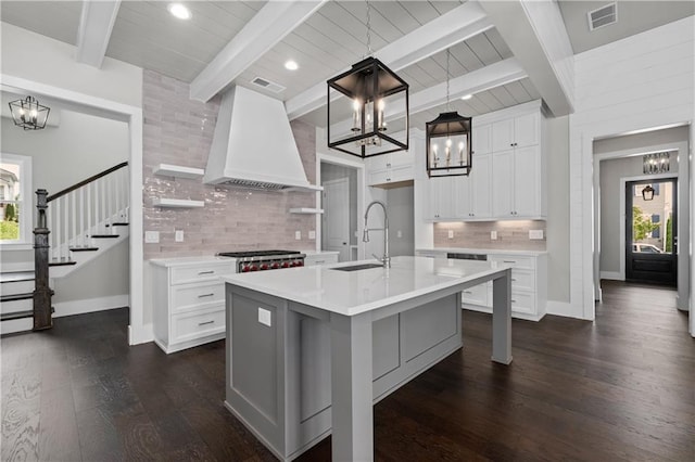 kitchen with a healthy amount of sunlight, premium range hood, a chandelier, light countertops, and a sink