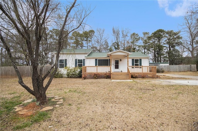 ranch-style house featuring a front yard, fence, and a wooden deck