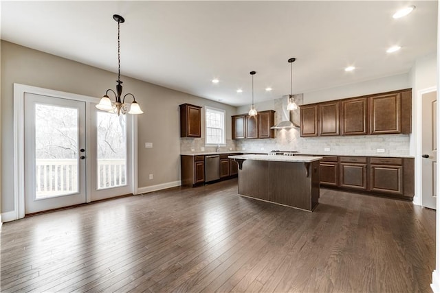 kitchen featuring wall chimney range hood, dark wood-type flooring, and a healthy amount of sunlight