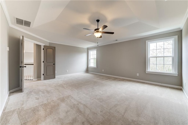 carpeted spare room featuring a tray ceiling, crown molding, and ceiling fan