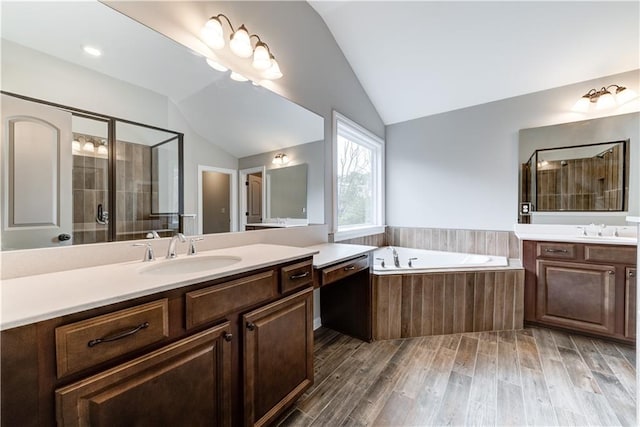 bathroom with shower with separate bathtub, wood-type flooring, double sink vanity, and vaulted ceiling