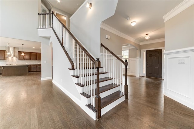 stairway with a high ceiling, dark hardwood / wood-style floors, and ornamental molding