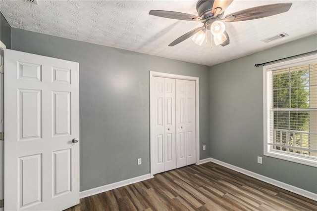unfurnished bedroom featuring a closet, dark wood-style flooring, baseboards, and visible vents