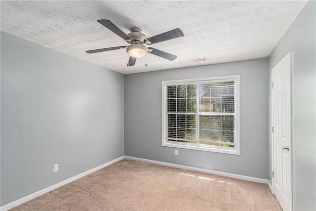 carpeted empty room featuring a textured ceiling, baseboards, a ceiling fan, and visible vents