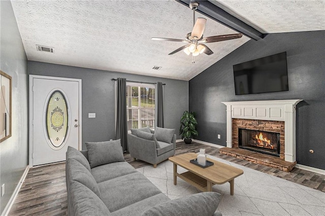 living room featuring a fireplace, visible vents, ceiling fan, vaulted ceiling with beams, and wood finished floors