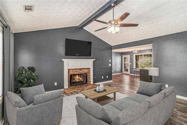 living area featuring baseboards, a lit fireplace, visible vents, ceiling fan, and wood finished floors