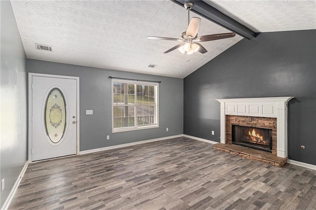 unfurnished living room with a stone fireplace, visible vents, ceiling fan, and wood finished floors