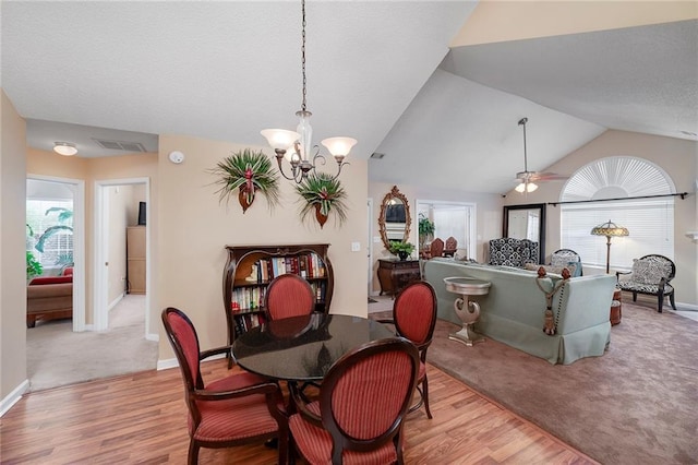 dining room with lofted ceiling, ceiling fan with notable chandelier, and light hardwood / wood-style floors