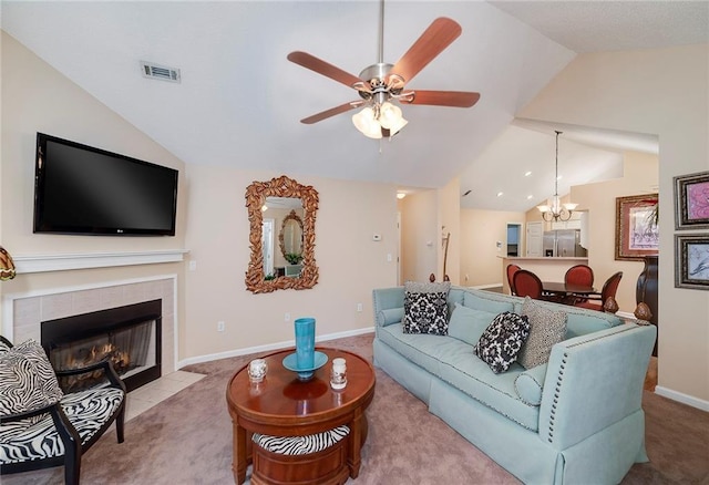 carpeted living room featuring a tile fireplace, vaulted ceiling, and ceiling fan with notable chandelier