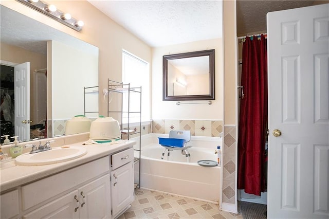 bathroom with vanity, a textured ceiling, and a bath