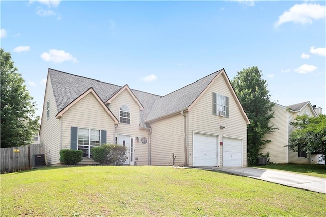 traditional-style house with a front lawn, fence, roof with shingles, an attached garage, and driveway