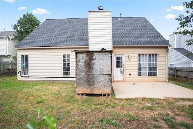 rear view of house with fence, a patio, and a lawn