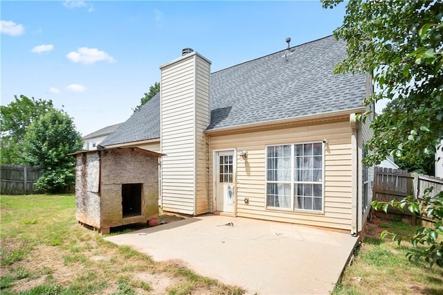 rear view of house with a patio, roof with shingles, fence, and a chimney