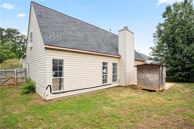 back of property featuring fence, a shingled roof, and a yard