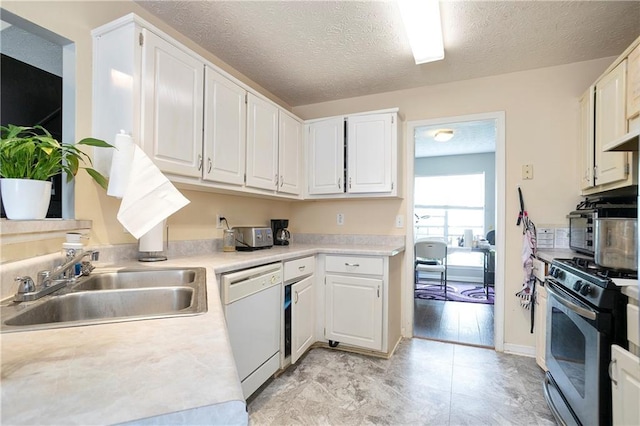 kitchen featuring white dishwasher, stainless steel gas range, a textured ceiling, white cabinets, and a sink