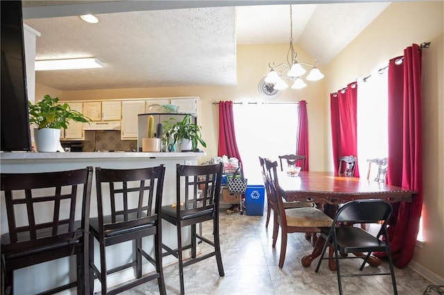 dining area with lofted ceiling, a textured ceiling, and a chandelier