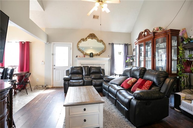 living room featuring ceiling fan, a fireplace, lofted ceiling, dark wood-type flooring, and visible vents