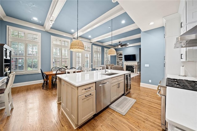 kitchen featuring sink, decorative light fixtures, light hardwood / wood-style flooring, appliances with stainless steel finishes, and a kitchen island with sink