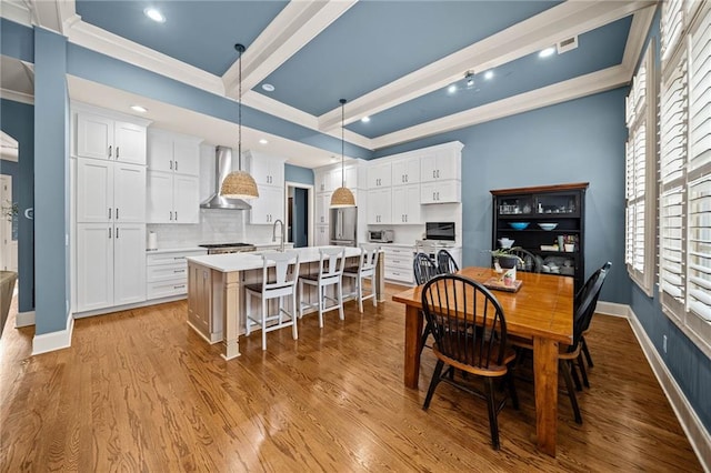 dining area featuring beamed ceiling, sink, crown molding, and light hardwood / wood-style floors