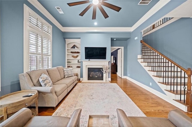 living room featuring hardwood / wood-style flooring, built in features, and ceiling fan