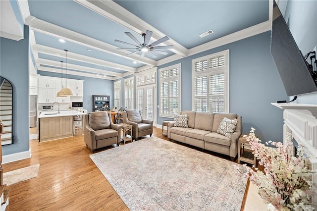 living room featuring sink, ornamental molding, ceiling fan, beam ceiling, and light hardwood / wood-style flooring