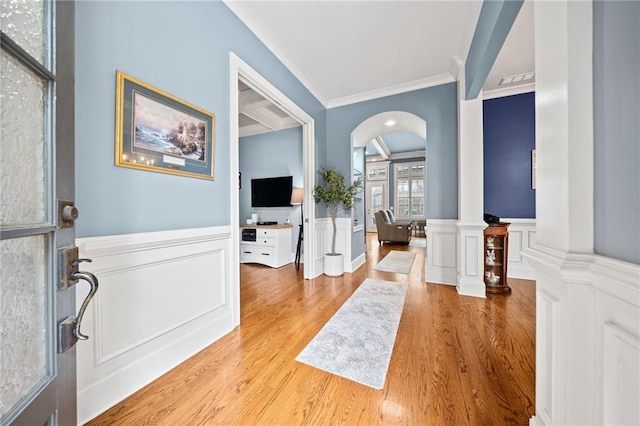 foyer entrance featuring crown molding, light hardwood / wood-style flooring, and ornate columns