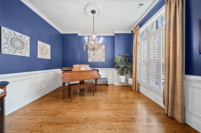 dining space with an inviting chandelier, ornamental molding, and wood-type flooring