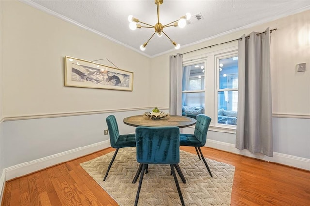 dining area with light wood-style flooring, a notable chandelier, baseboards, and ornamental molding