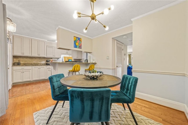 dining area featuring a textured ceiling, a notable chandelier, light wood-style flooring, and ornamental molding