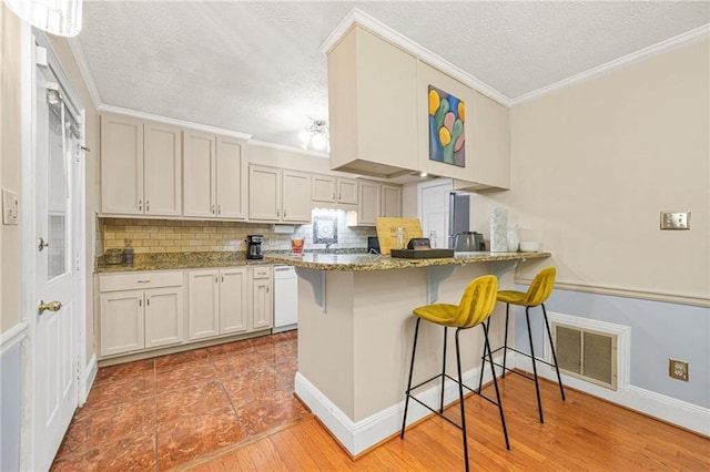 kitchen with a kitchen bar, visible vents, and ornamental molding