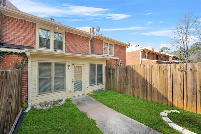 exterior space with a front lawn, fence, and brick siding