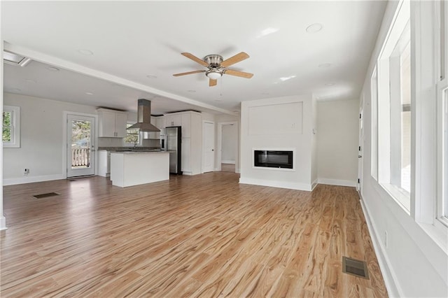 unfurnished living room featuring ceiling fan and light hardwood / wood-style flooring