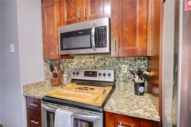 1638 River Trce, Auburn, GA 30011 - kitchen featuring appliances with stainless steel finishes, backsplash, light stone countertops, and reddish brown cabinets