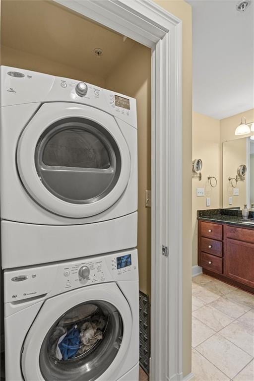 clothes washing area with stacked washer / drying machine, light tile patterned floors, and sink