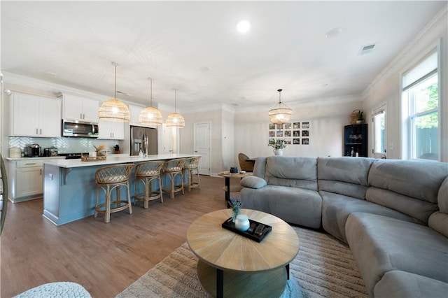 living room featuring crown molding, sink, and light hardwood / wood-style floors