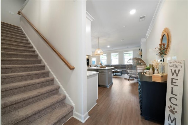 stairs with wood-type flooring and crown molding