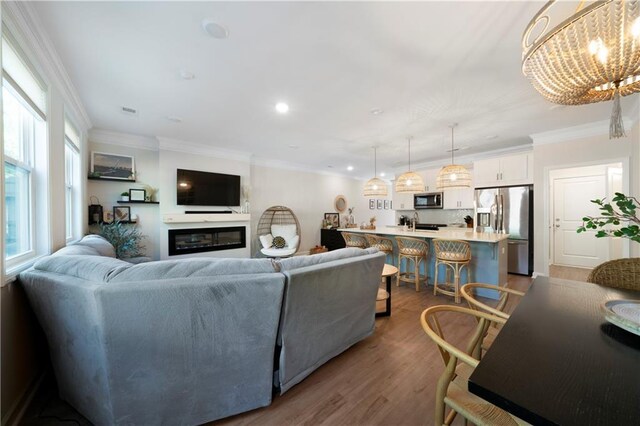 living room with ornamental molding, a notable chandelier, and hardwood / wood-style floors