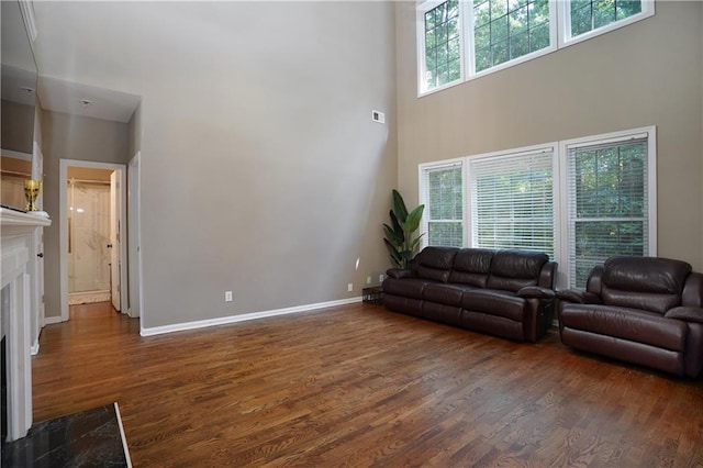 7185 Hartsfield Pl, Suwanee, GA 30024 - living area featuring a high ceiling, dark wood finished floors, a high end fireplace, and baseboards
