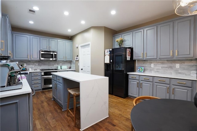 7185 Hartsfield Pl, Suwanee, GA 30024 - kitchen featuring black refrigerator with ice dispenser, stainless steel microwave, range, a kitchen island, and gray cabinets