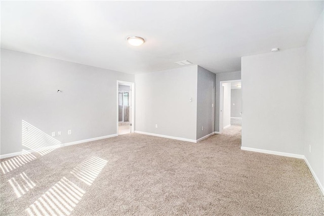spare room featuring light colored carpet and baseboards