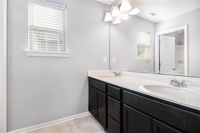 full bath featuring double vanity, tile patterned flooring, and baseboards