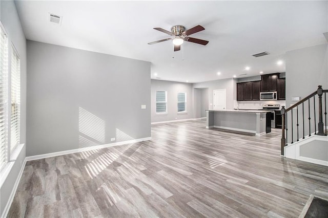 unfurnished living room featuring light wood-style floors, ceiling fan, stairway, baseboards, and recessed lighting