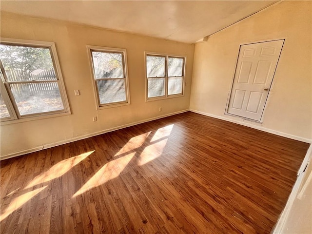 spare room featuring dark hardwood / wood-style flooring and vaulted ceiling