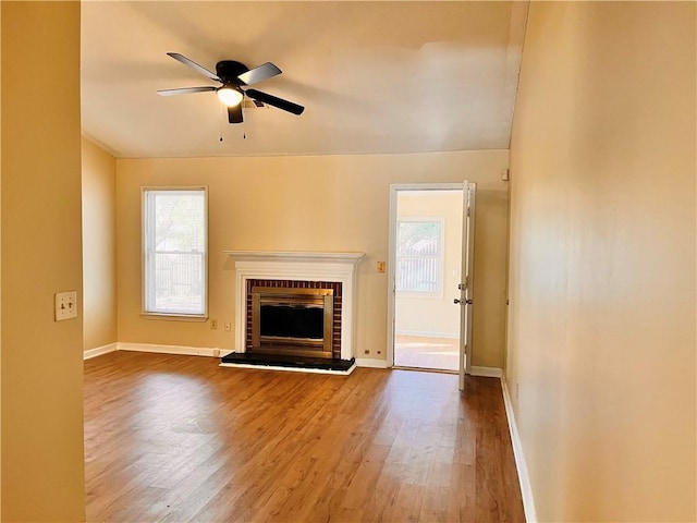 unfurnished living room with hardwood / wood-style flooring, a fireplace, ceiling fan, and plenty of natural light