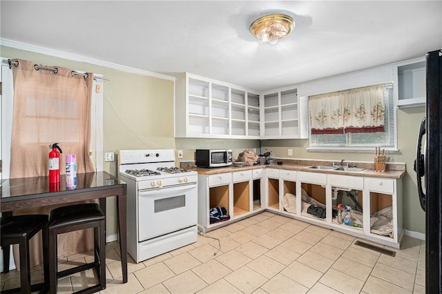 kitchen featuring open shelves, stainless steel microwave, white gas range oven, and a sink