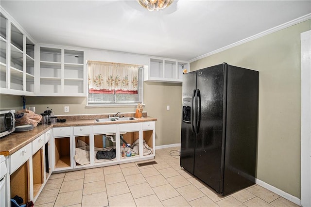 kitchen with baseboards, light tile patterned flooring, black refrigerator with ice dispenser, and a sink