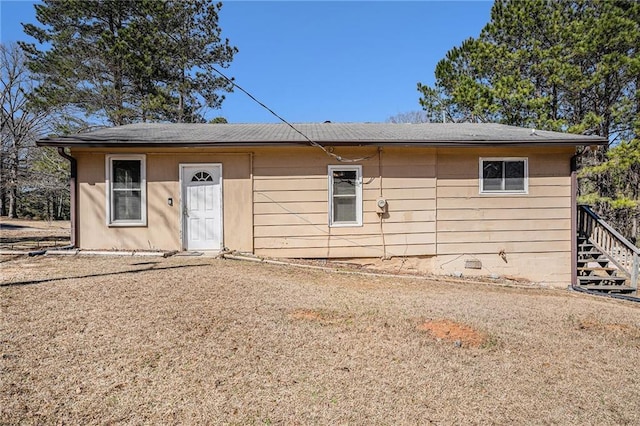 rear view of property featuring crawl space and stairs