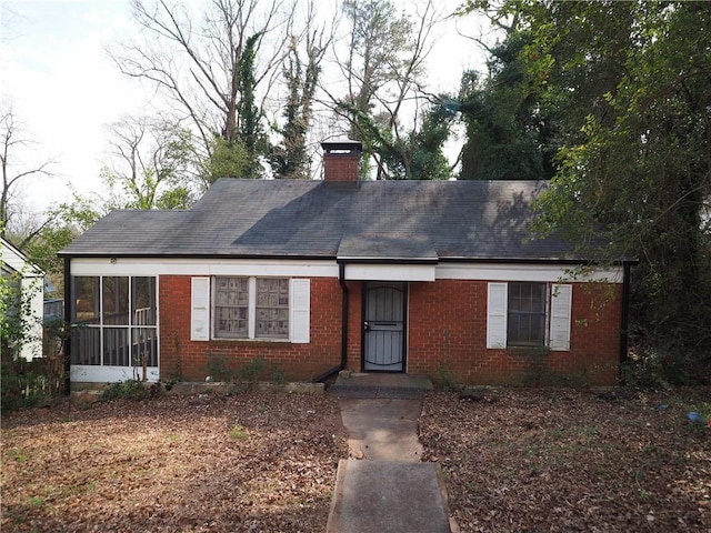 single story home with brick siding and a chimney