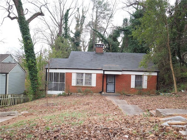 single story home featuring a chimney, fence, and brick siding