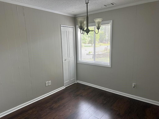unfurnished dining area with crown molding, dark wood-style flooring, an inviting chandelier, a textured ceiling, and visible vents